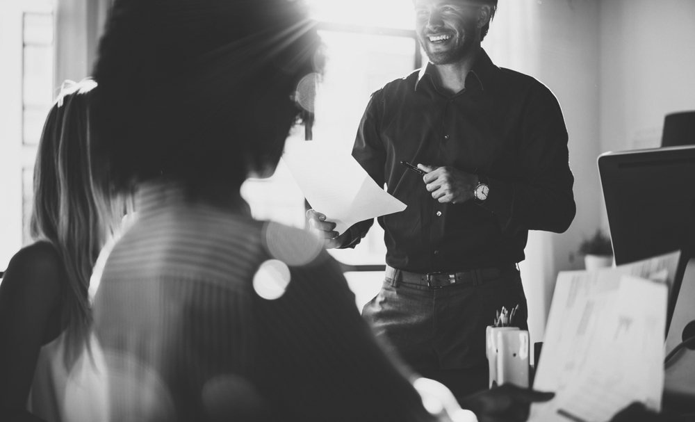 shutterstock_530013196-bw people talking at desk in office