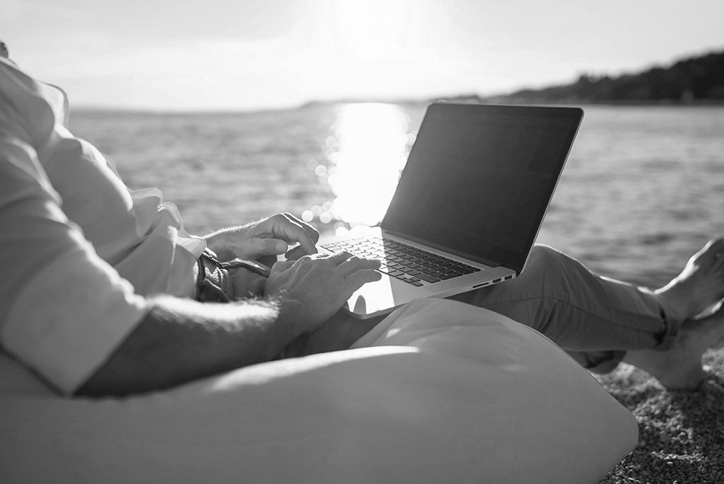 man working at computer on beach