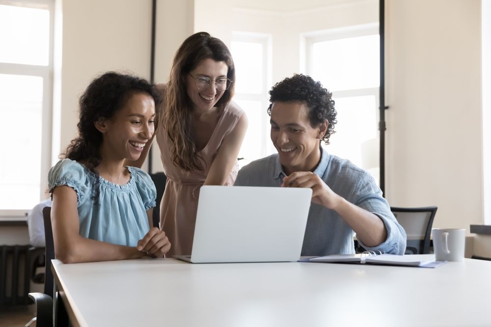 Three,Multiracial,Colleagues,Use,Laptop,Speaking,On,Project,,Discuss,Collaborative