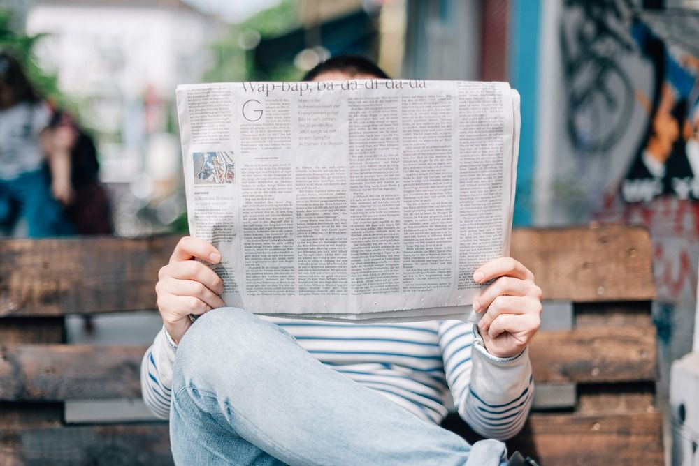 man-sitting-on-bench-reading-newspaper