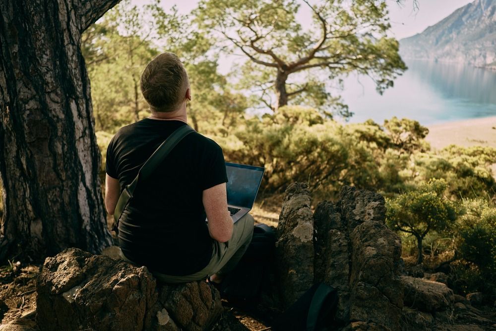 man-on-laptop-overlooking-lake